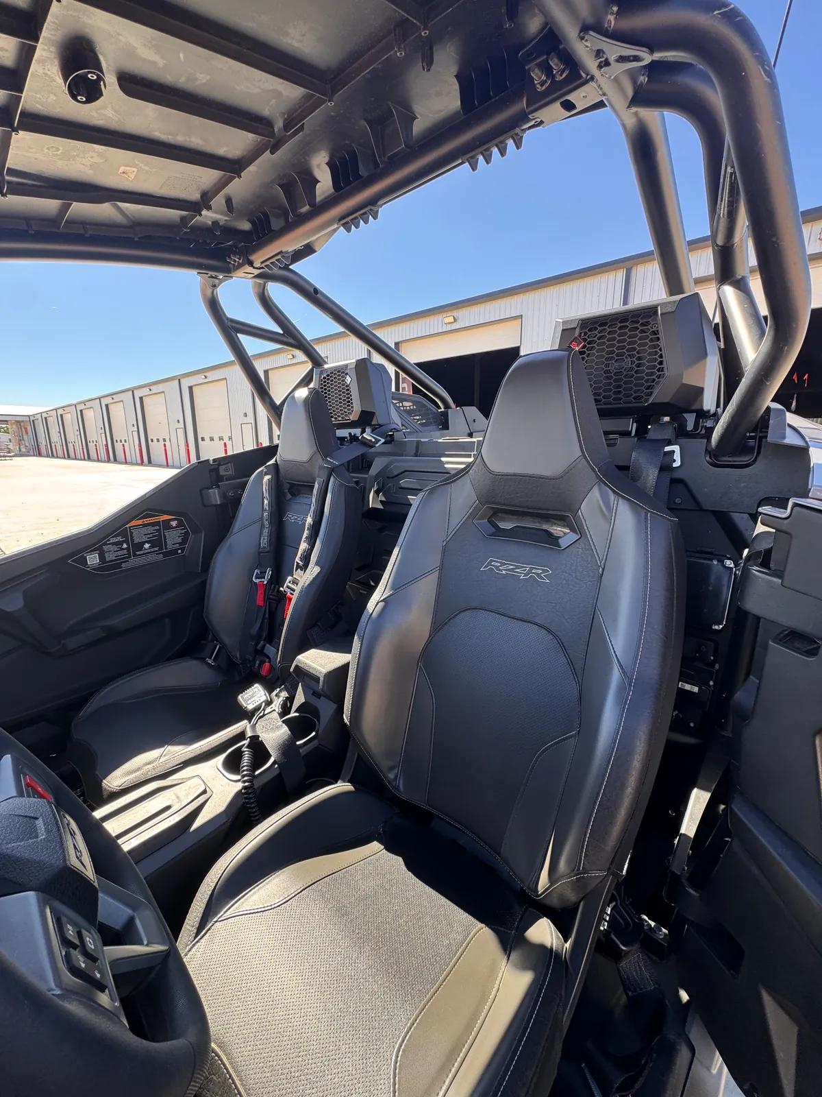 Inside the RZR Pro S Ultimate "Ninja": two RZR bucket seats with harness belts and speaker pods mounted behind the seats under the roll cage